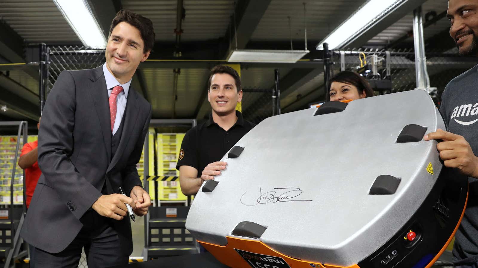 Canada’s Prime Minister Justin Trudeau signs a robotic unit during a tour of the Amazon Fulfillment Centre in Brampton, Ontario Canada, October 20, 2016.
