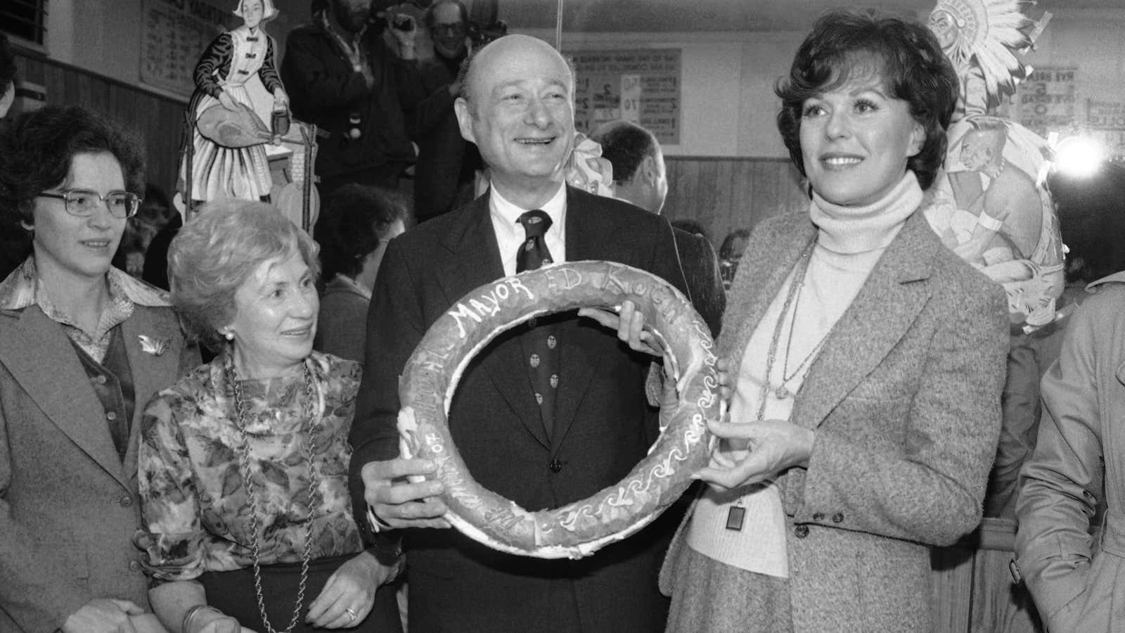 Then mayor-elect Edward Koch and Miss America Bess Myerson pose with New York’s real icon: The bagel.