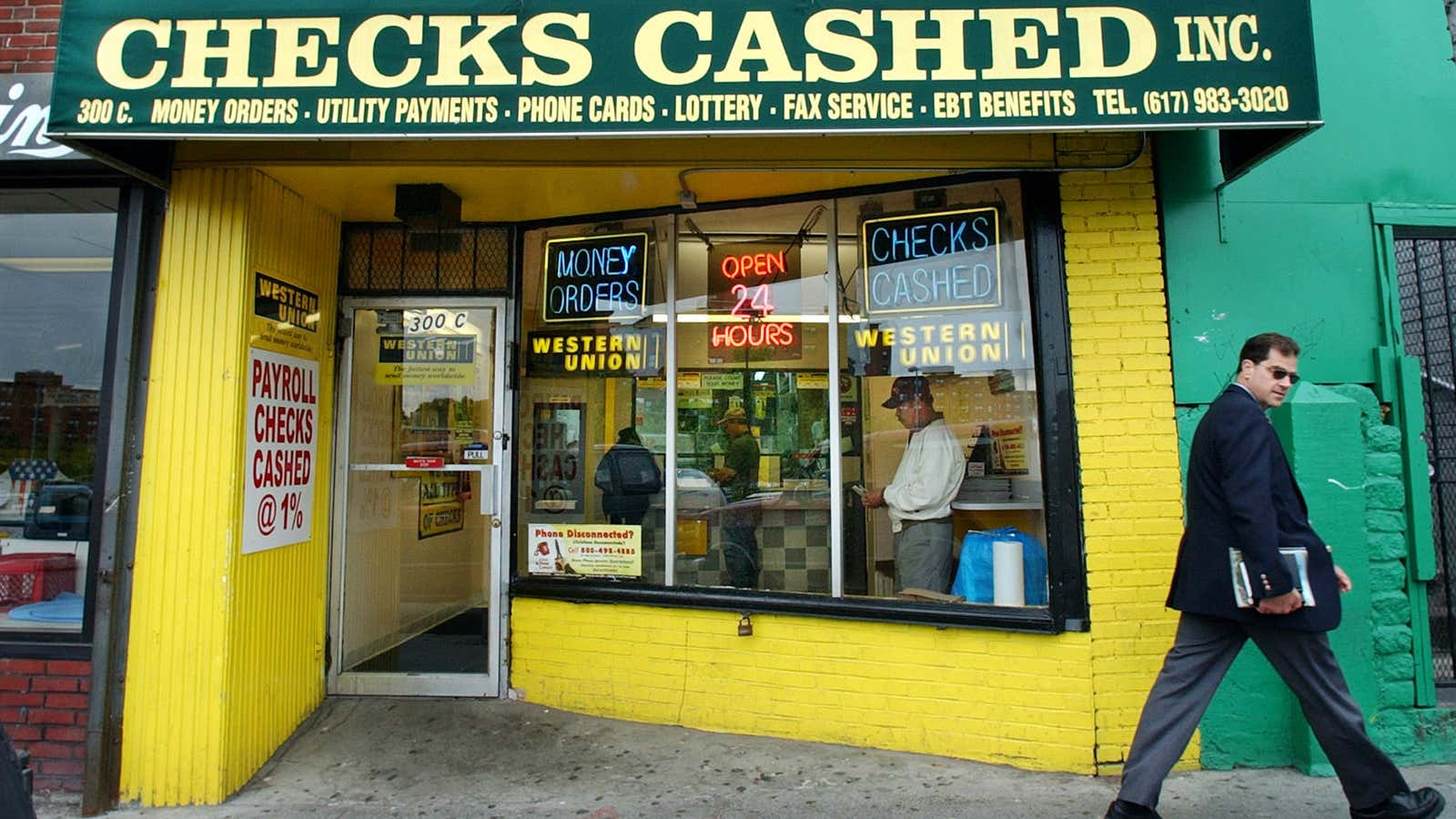 A pedestrian walks by a check-cashing store in Boston’s Jamaica Plain district, Thursday, May 22, 2003. Check-cashing stores, which sell millions of dollars of lottery…