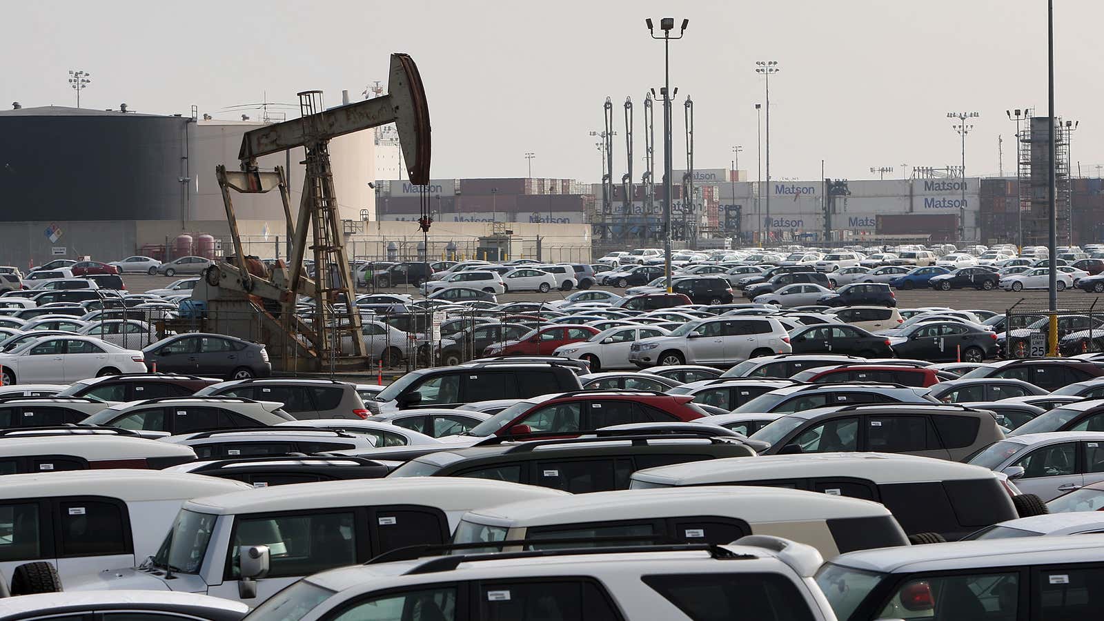 An oil well extracts light sweet crude from the ground beneath newly imported cars at the Port of Long Beach.