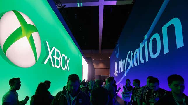 Visitors walk past giant signs of Xbox and PlayStation at an E3 conference. 