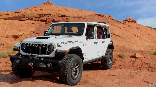 A photo of a white Jeep Wrangler on a rock. 