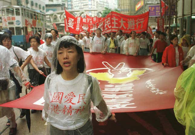 Pro-democracy activists of Hong Kong Alliance carry a red banner reading "Democracy for Hong Kong" during their march in a street in Hong Kong, China, Tuesday, July 1, 1997. Democrats held the first large post-handover protest under the Chinese rule. (AP Photo/David Brauchli)