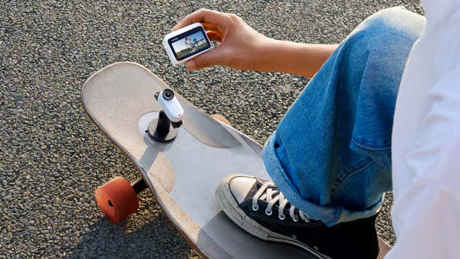 Una persona con la cámara Insta360 GO 3 conectada a un soporte en una patineta usando el accesorio Pod para ver una vista previa en vivo de lo que está grabando.