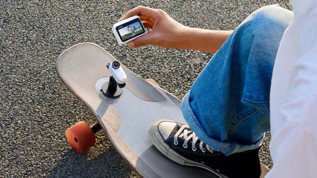 A person with the Insta360 GO 3 camera attached to a mount on a skateboard using the Pod accessory to view a live-preview of what it's recording.