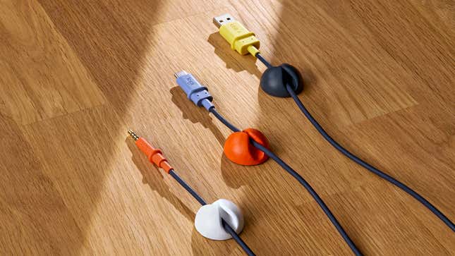 The three cable connectivity options available for the Logitech Zone Learn headphones on a wooden desk: 3.5mm audio, USB-C, and USB-A.