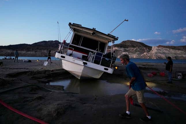 A man tries to free his stranded houseboat on Lake Mead.