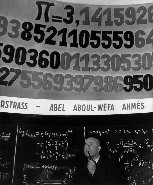 A man in front of a board showing pi in the 1960s.