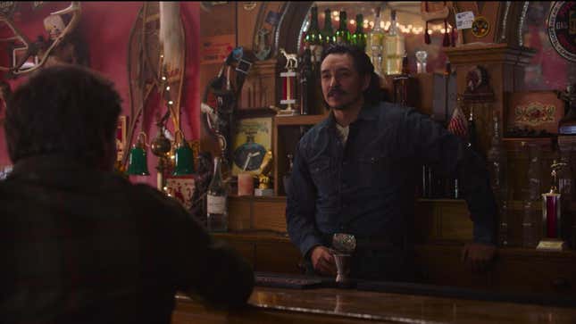 Tommy stands behind a bar facing Joel in a scene from HBO's The Last of Us.