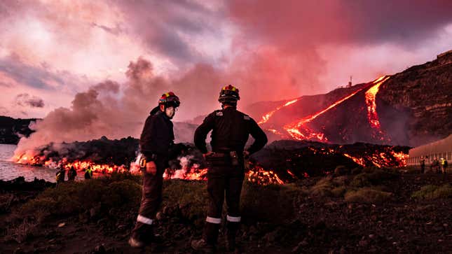 Members of a military emergency unit stand as lava flows from a volcano reaching the sea on the Canary island of La Palma, Spain.