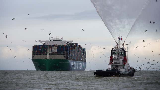A photo of a large container ship with a tug boat escort. 