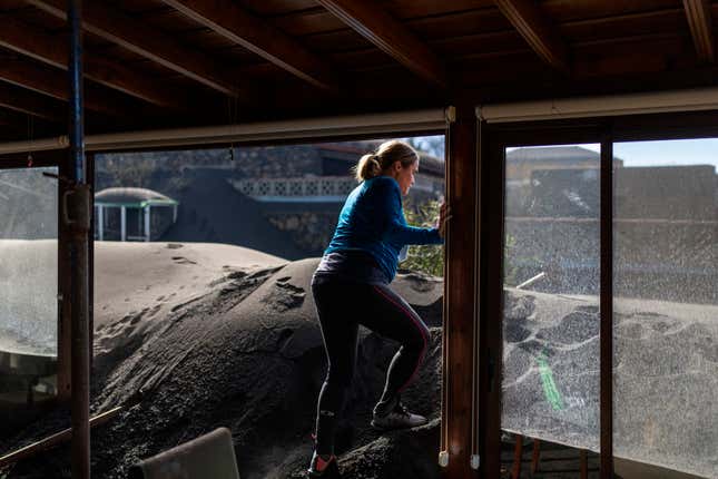Cristina Vera leaves her house covered with ash from volcano eruptions after collecting her last belongings.