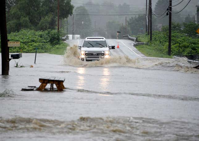 A truck drives through deep floodwaters from the Dog River on Route 12 in Berlin, Vt. on Monday, July 10, 2023.