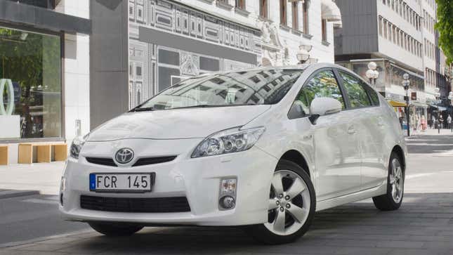 A photo of a white Toyota Prius parked on a city street. 