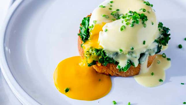 A serving of eggs benedict featuring Yo Egg's plant-based poached egg with the yellow yolk running out onto the plate.