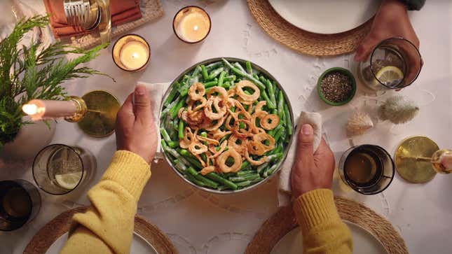 Green bean casserole being placed on Thanksgiving table