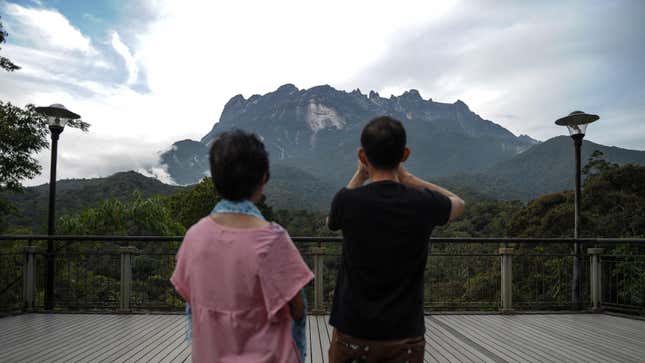  tourist (R) takes pictures of Malaysia's Mount Kinabalu.