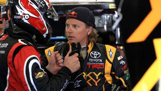 Kimi Räikkönen speaks to a mechanic in a garage at a NASCAR race in 2011 