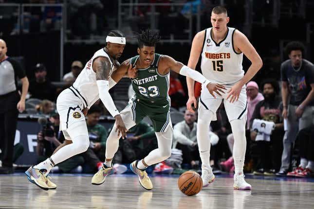 Mar 16, 2023; Detroit, Michigan, USA; Denver Nuggets guard Kentavious Caldwell-Pope (5) (left) knocks the ball away from Detroit Pistons guard Jaden Ivey (23) as Denver Nuggets center Nikola Jokic (15) watches in the first quarter at Little Caesars Arena.
