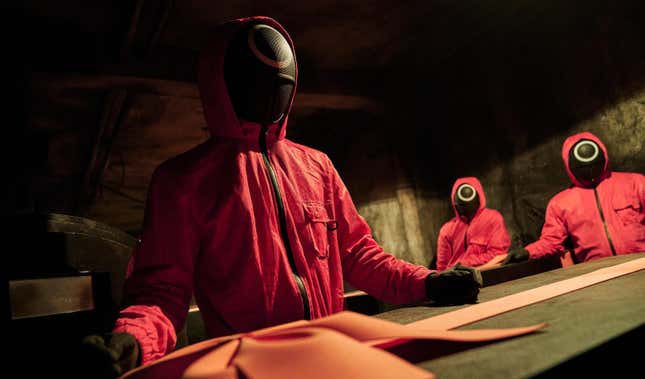 The pink-clad henchmen in Squid Game prepare a coffin.