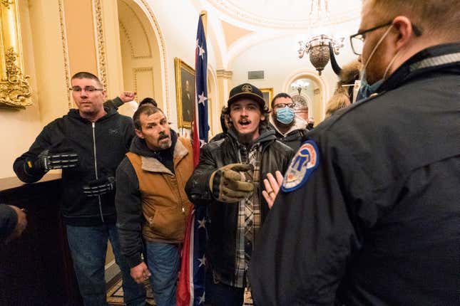 Kevin Seefried, second from left, holds a Confederate battle flag as he and other insurrectionists loyal to President Donald Trump are confronted by U.S. Capitol Police officers outside the Senate Chamber inside the Capitol in Washington, Jan. 6, 2021.