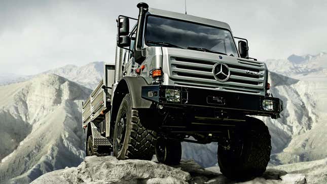 A silver Unimog truck drives up a cliff