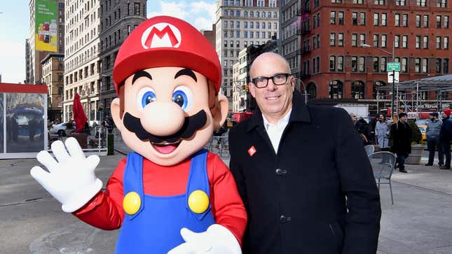 A person wearing a Mario mascot outfit stands next to Nintendo president Doug Bowser smiling at the camera in a backdrop of Manhattan