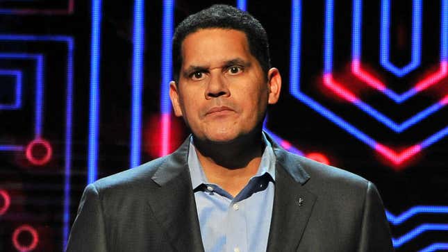 Reggie Fils-Aime wears a suit with bright neon blue lights behind him. 