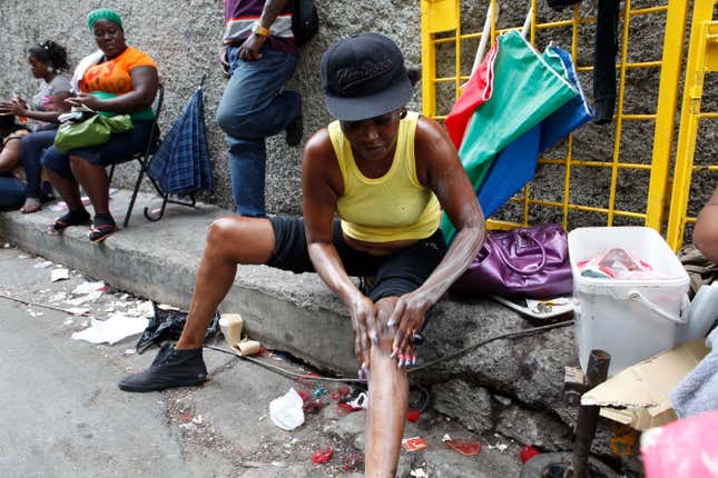 A woman applies skin lightening cream to her legs in downtown Kingston, Jamaica.