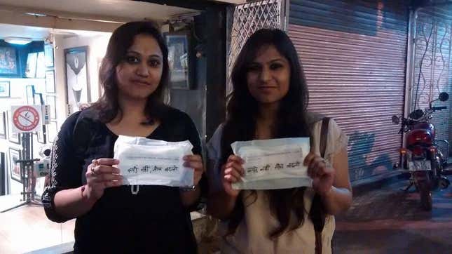 Two girls hold up sanitary napkins in Hauz Khas Village, Delhi.