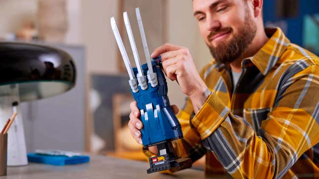 A person in a plaid shirt holding the Lego Marvel Wolverine's Adamantium Claws set and posing one of the fingers.