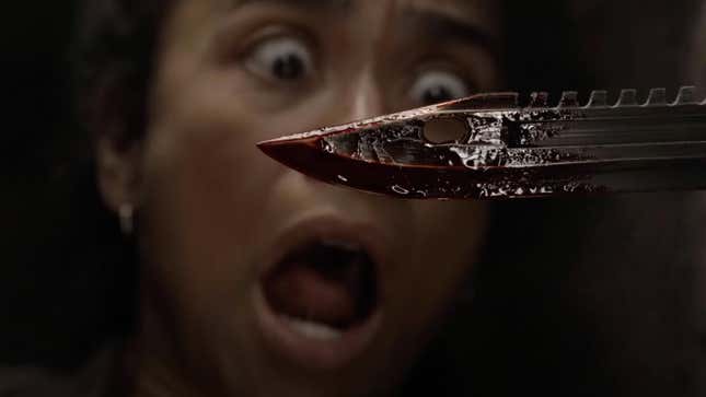 This image from The Walking Dead's final season depicts a bloody blade in the foreground, and a person's terrified face in the background.