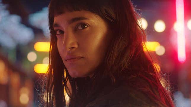Sofia Boutella, wearing short bangs and with bright lights behind her, in a scene from Prisoners of the Ghostland.