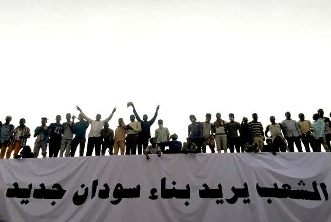 Sudanese demonstrators stand next to a banner reading in Arabic "People want to build new Sudan" as they chant slogans during a protest rally demanding Sudanese President Omar Al-Bashir to step down, outside Defence Ministry in Khartoum, Sudan April 9, 2019.
