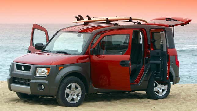 A photo of a red Honda Element with a surfboard tied to the roof. 