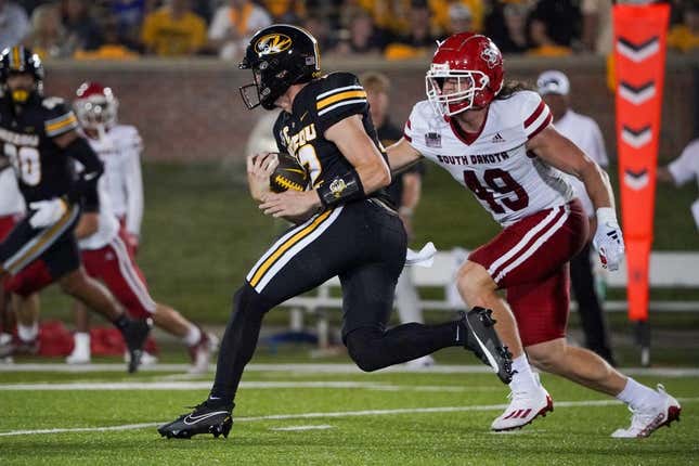Aug 31, 2023; Columbia, Missouri, USA; Missouri Tigers quarterback Brady Cook (12) runs the ball as South Dakota Coyotes linebacker Brock Mogensen (49) defends during the first half at Faurot Field at Memorial Stadium.