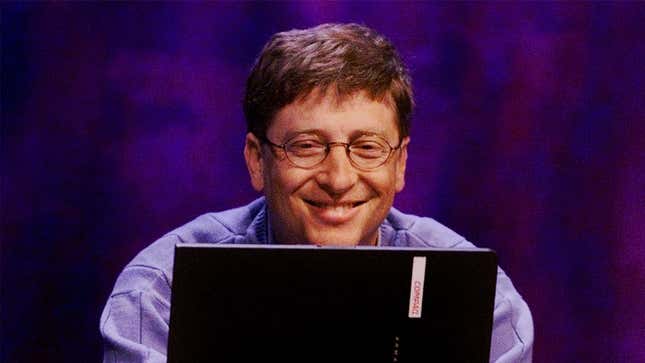 A photograph of Bill Gates smiling while working on a laptop. 