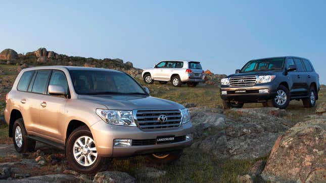 Three Toyota Land Cruiser SUVs parked on a hill