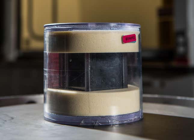 A cylindrical case with a radioactive cube inside.