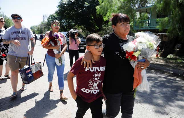 A woman and a childarrive to Robb Elementary school with flowers, the day after a gunman killed 19 children and two teachers at the school in Uvalde, Texas