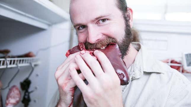 Man with ponytail biting into raw meat
