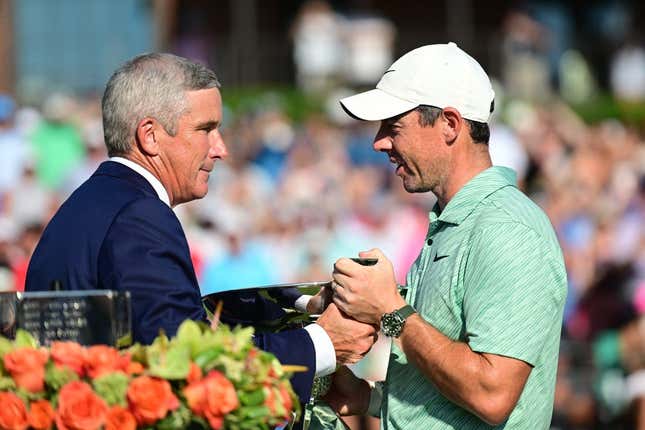 Aug 28, 2022; Atlanta, Georgia, USA; PGA commissioner Jay Monahan hands the FedEx Cup trophy to Rory McIlroy during the final round of the TOUR Championship golf tournament.