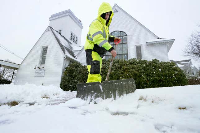 Worker Bayron Barrientos shovels snow off a path, Tuesday, Feb. 28, 2023, in front of a church, in Norwood, Massachusetts. 