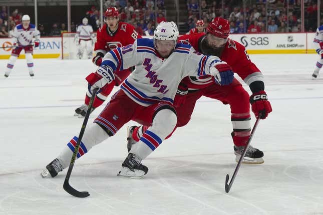 Mar 23, 2023; Raleigh, North Carolina, USA;  New York Rangers right wing Vladimir Tarasenko (91) tries to skates with the puck past Carolina Hurricanes defenseman Brent Burns (8) during the second period at PNC Arena.