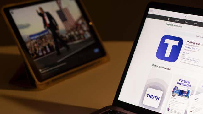 A laptop screen showing the App Store preview for Truth Social sitting next to a tablet screen with a blurred image of Donald Trump.