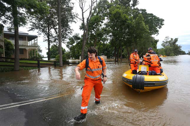 State Emergency Service crew members land a boat in front of homes after surveying floodwaters in Windsor on March 9, 2022 in Sydney, Australia.