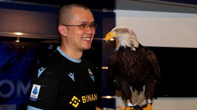 Binance CEO Chengpeng Zhao wearing a Binance logo on his shirt, holding an eagle.