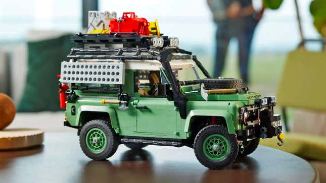 The Lego Land Rover Defender 90 model on a wooden table equipped with adventuring accessories.
