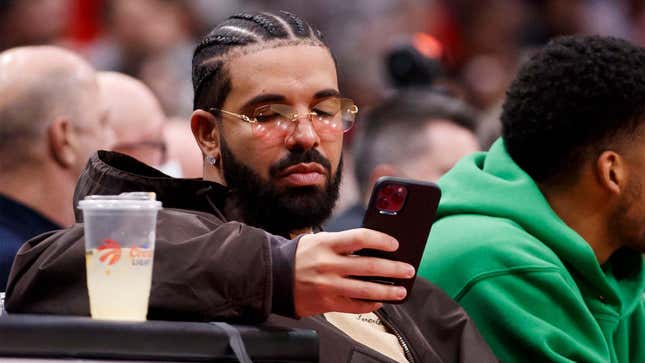 Drake, the rapper, looks at his phone during an NBA game. 