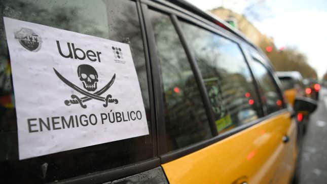 A placard reading “Uber public enemy” hangs from the window of a taxi on March 18, 2021 in Barcelona during a strike by taxis drivers organised against the ride-sharing service Uber. 
